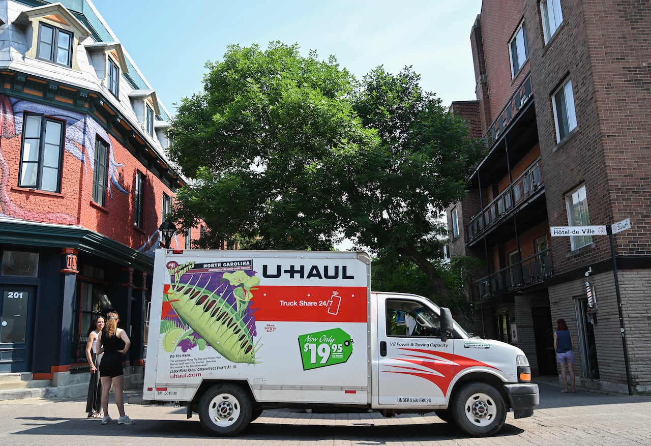 People stand next to a Uhaul truck on a sunny day.