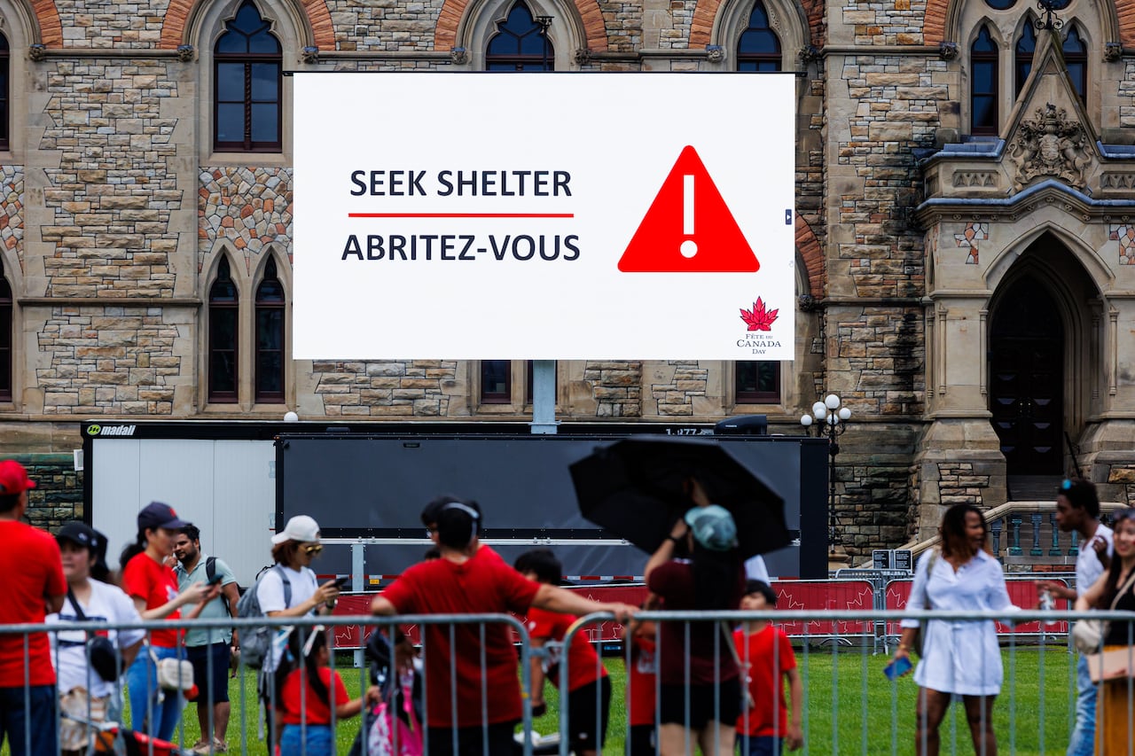 A screen reads Seek Shelter above people standing behind barricades