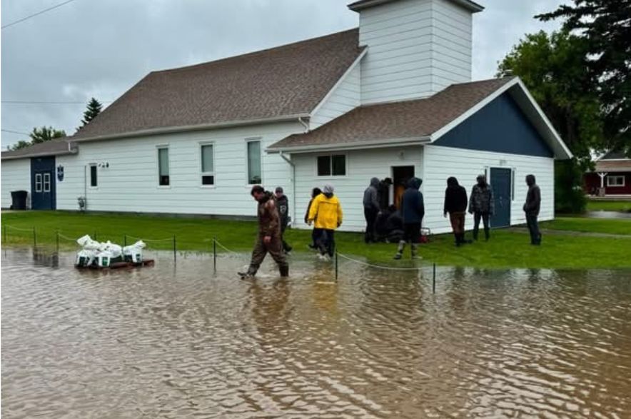 People walk through knee-deep floodwater outside a church in Norquay, Saskatchewan.