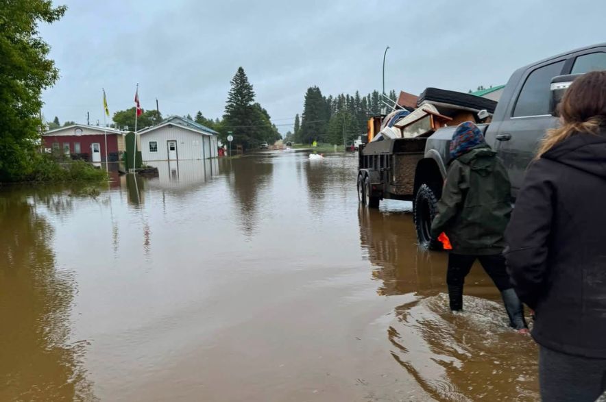 People walk through knee-deep floodwater outside a church in Norquay, Saskatchewan.