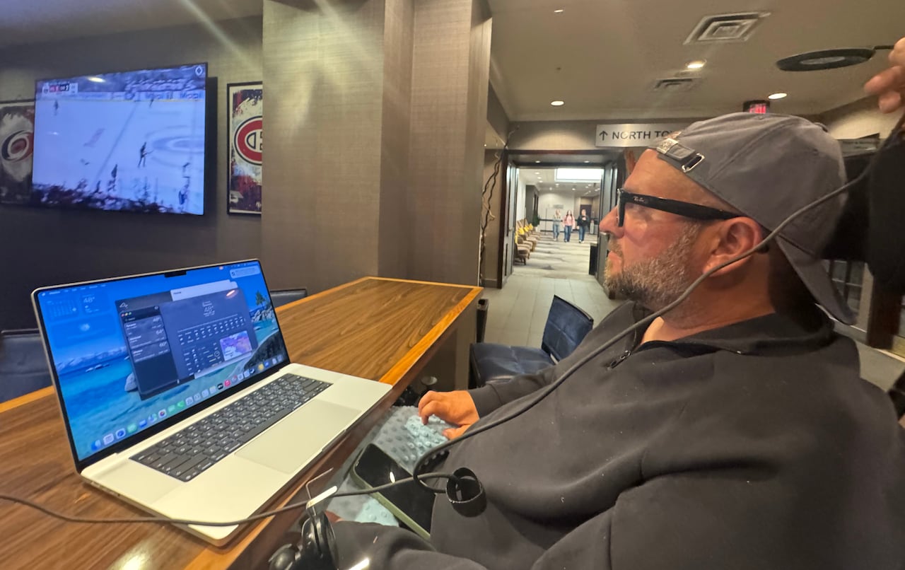 A man controls a laptop in a hospital corridor.