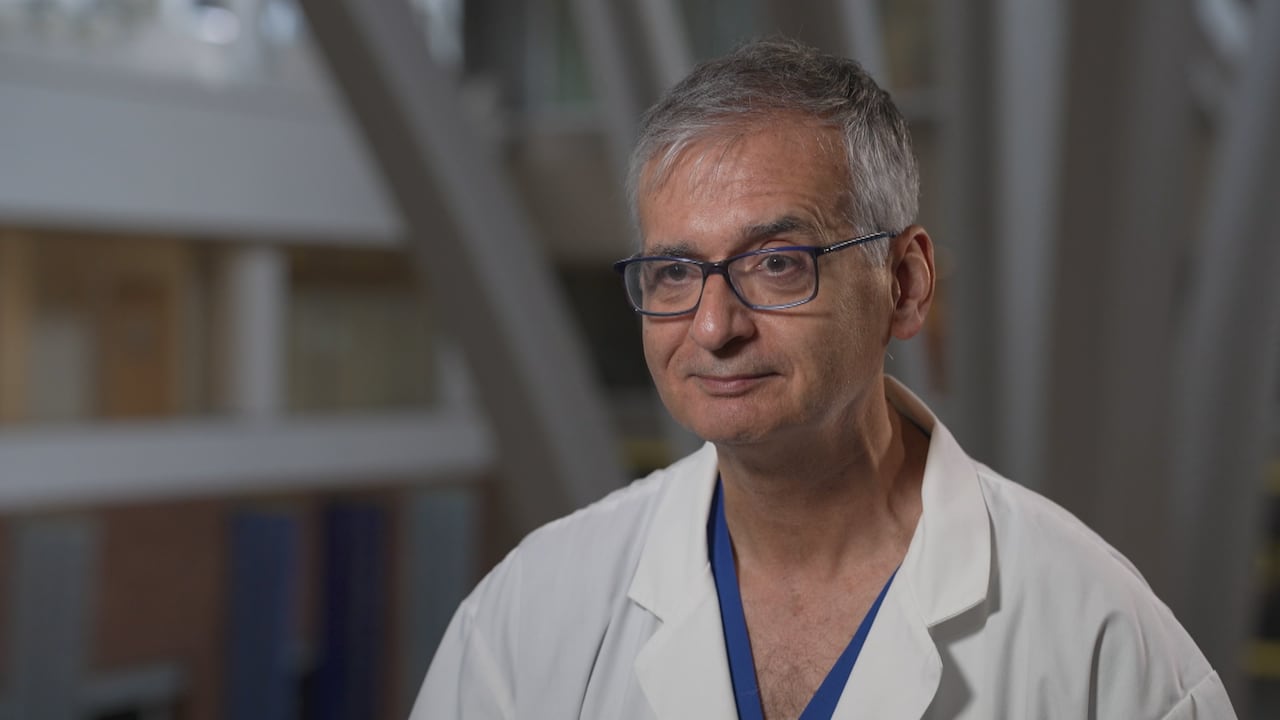 A man in a lab coat smiles.