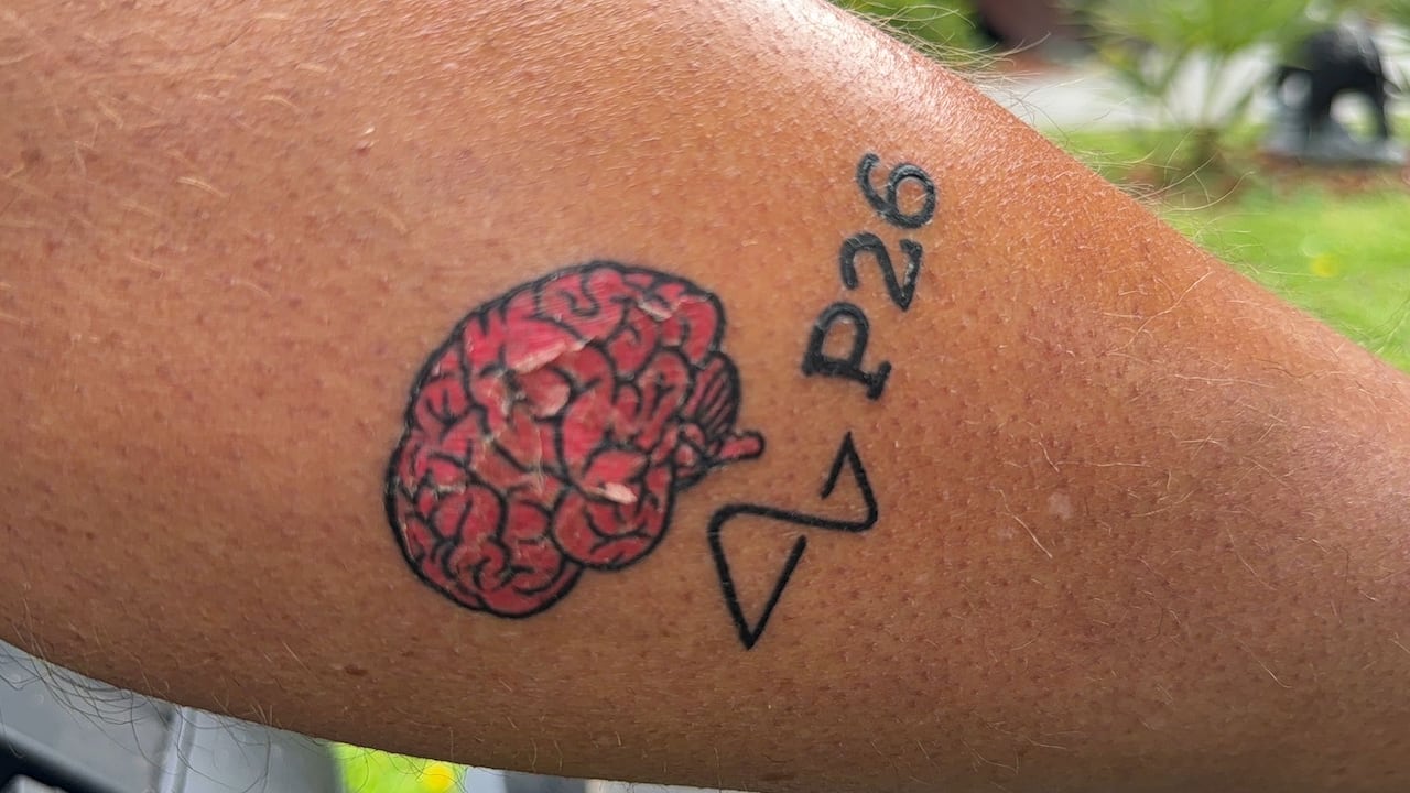 A tattoo on a person's leg with a pink human brain and the words 'P26'.