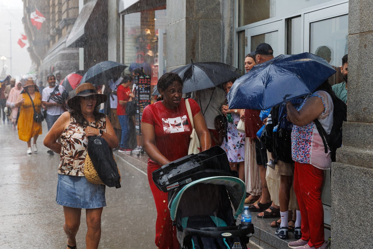 People hold umbrellas and walk through heavy rain.