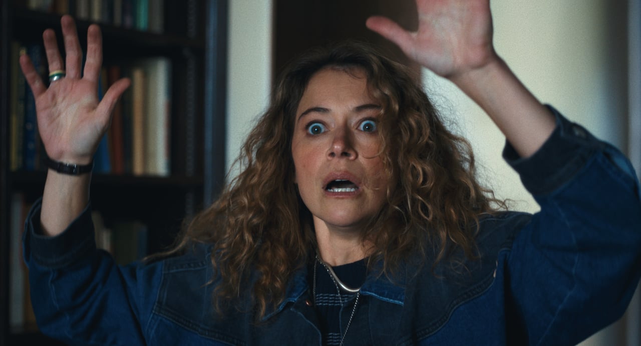 A harried-looking woman puts both her hands over her head.