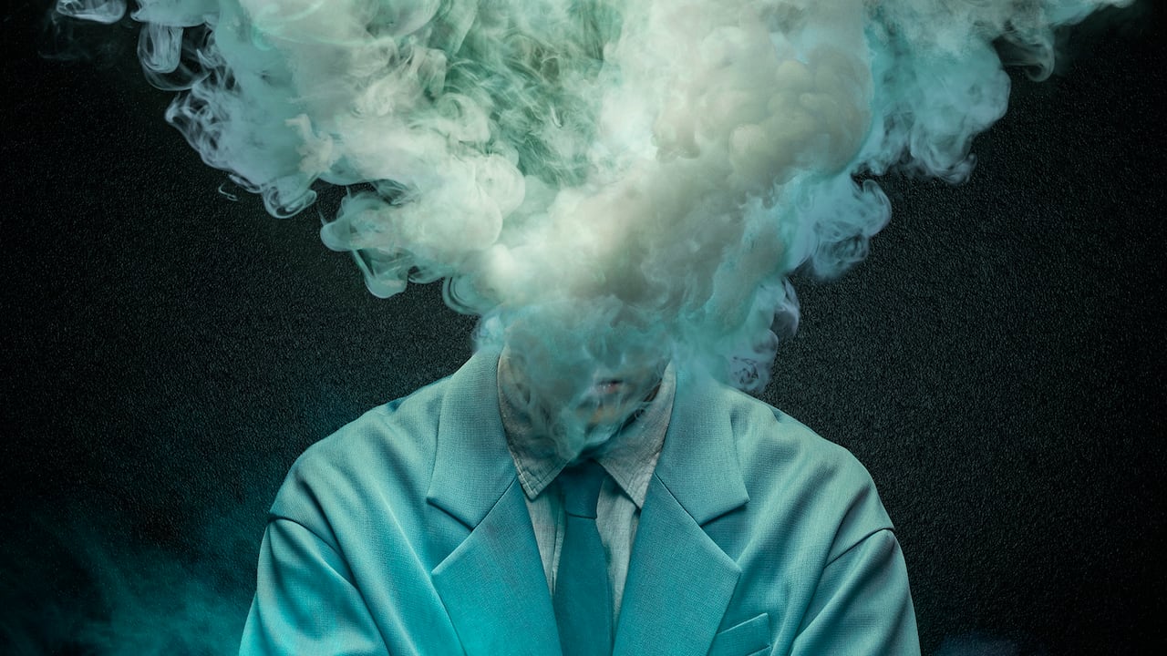 A plume of smoke is seen coming out of the collar of a suit.