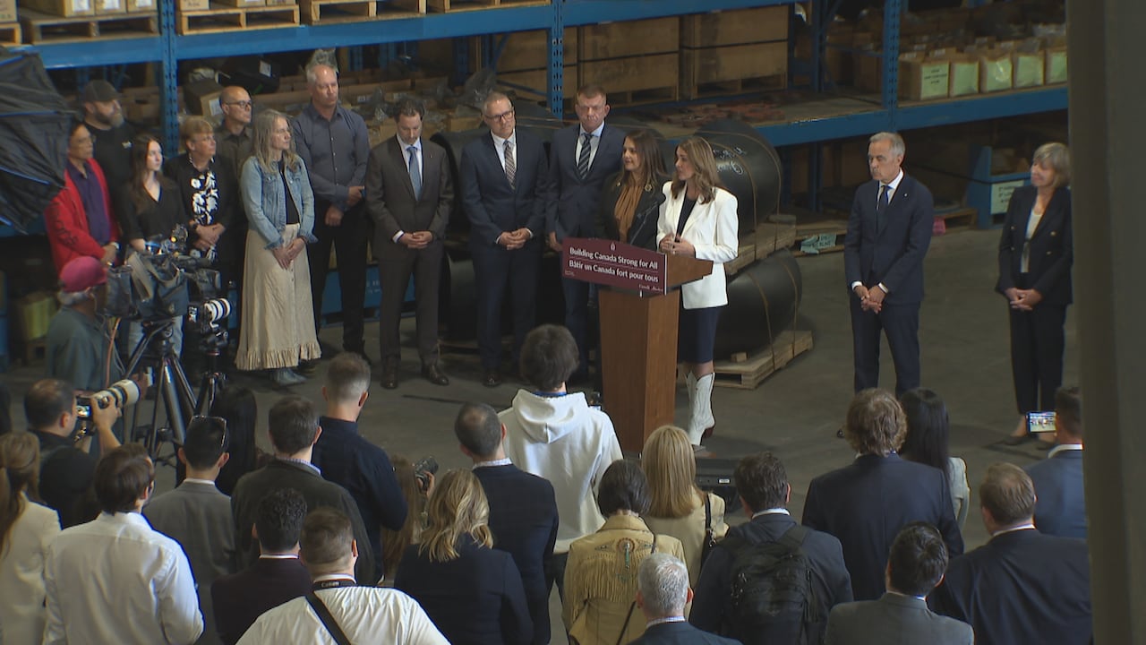 Danielle Smith stands at a podium in front of an audience of dozens of journalists and energy industry representatives.