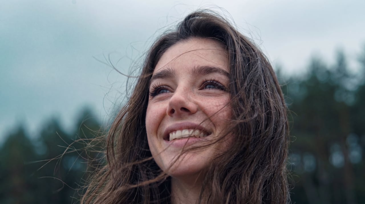 A smiling woman with her hair blowing in a breeze