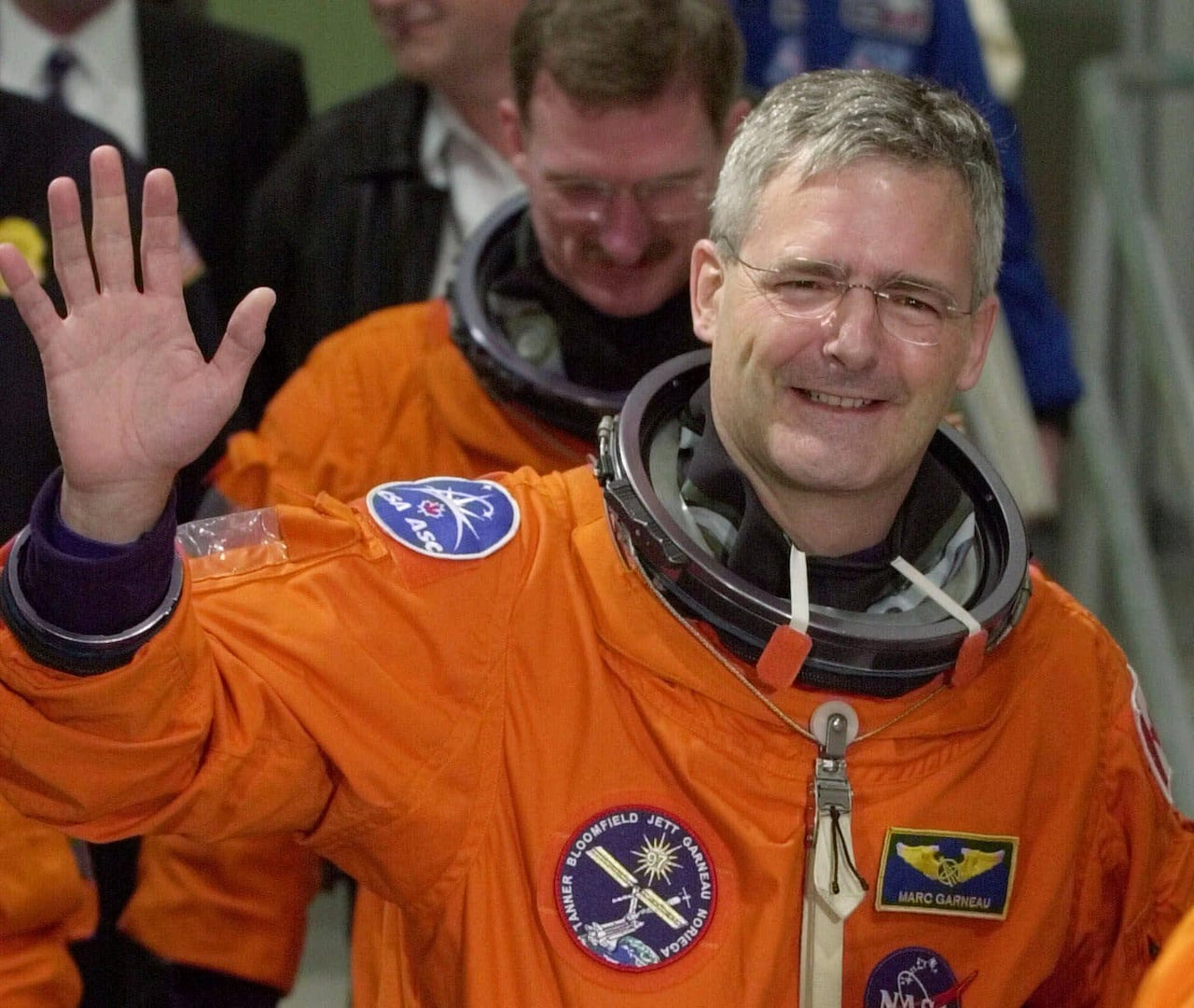 Marc Garneau, suited up for a spaceflight, waving to reporters in November 2000.