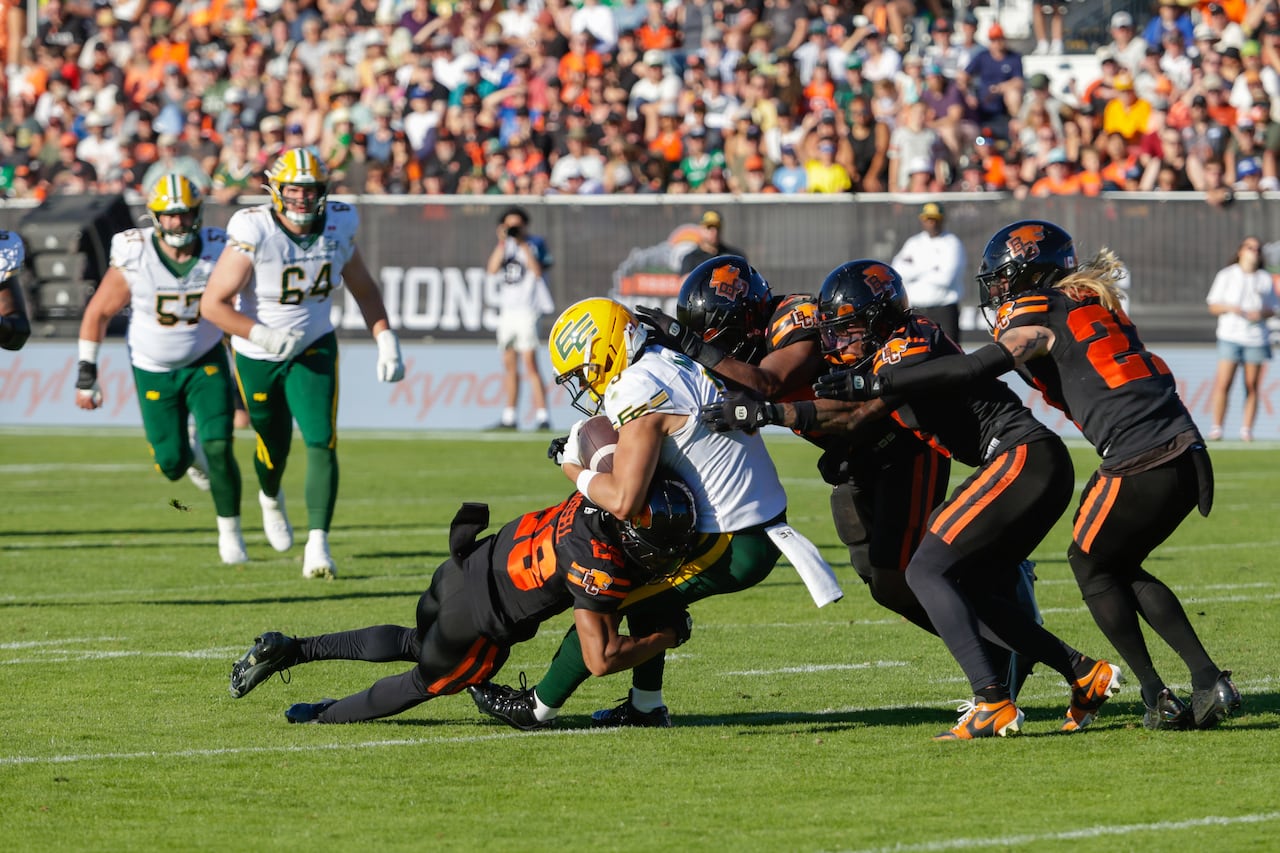 Men play football on a field.