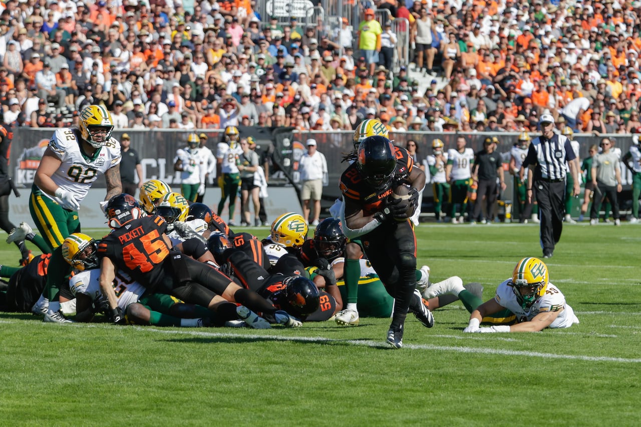 Men play football on a field.