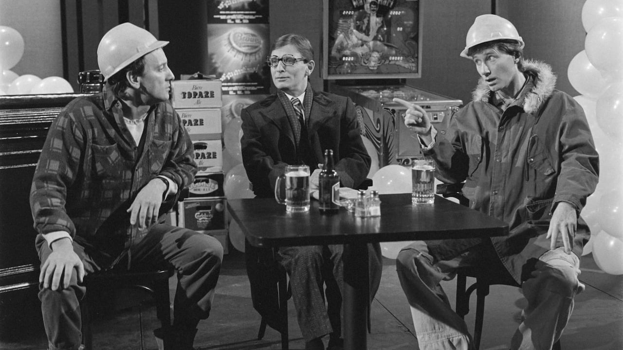 Three Quebec actors sit at a table drinking beers during a sketch.