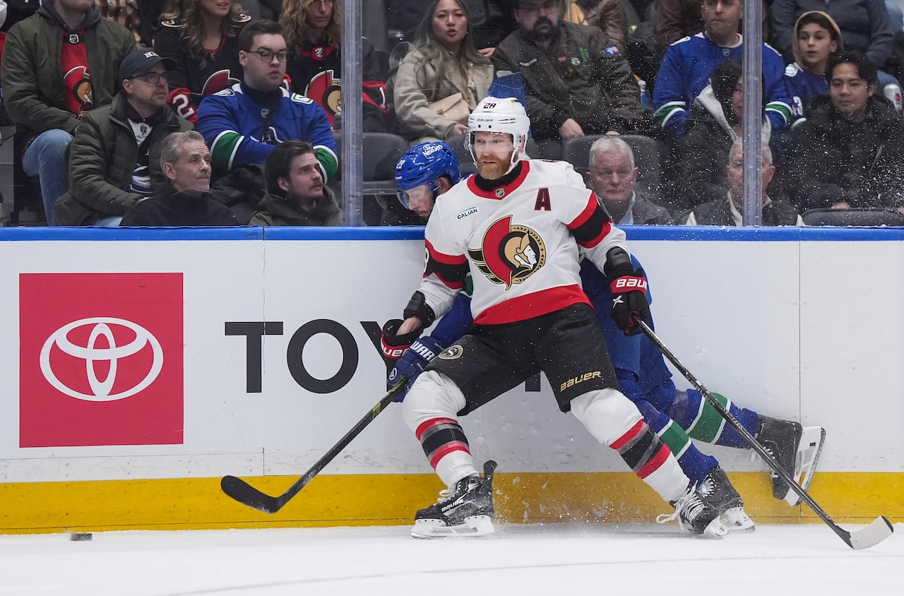 One hockey player checks another into the boards during a game.