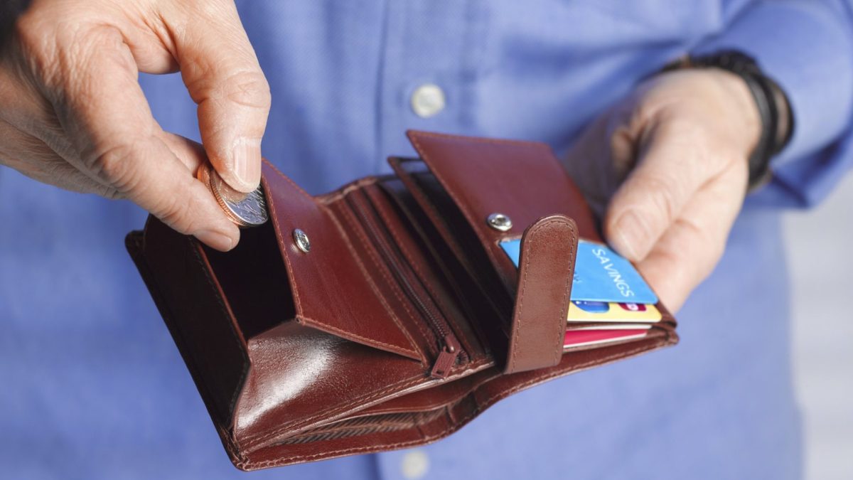 Close up of a man with a wallet putting coins inside