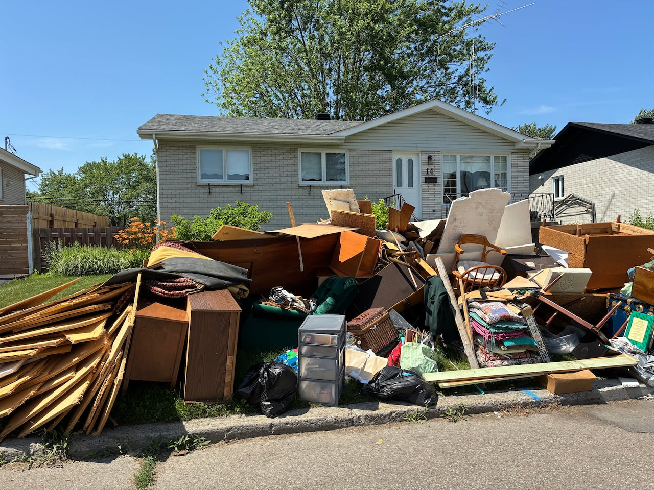photo of someones house with mounds of garbage outside, due to flooding.