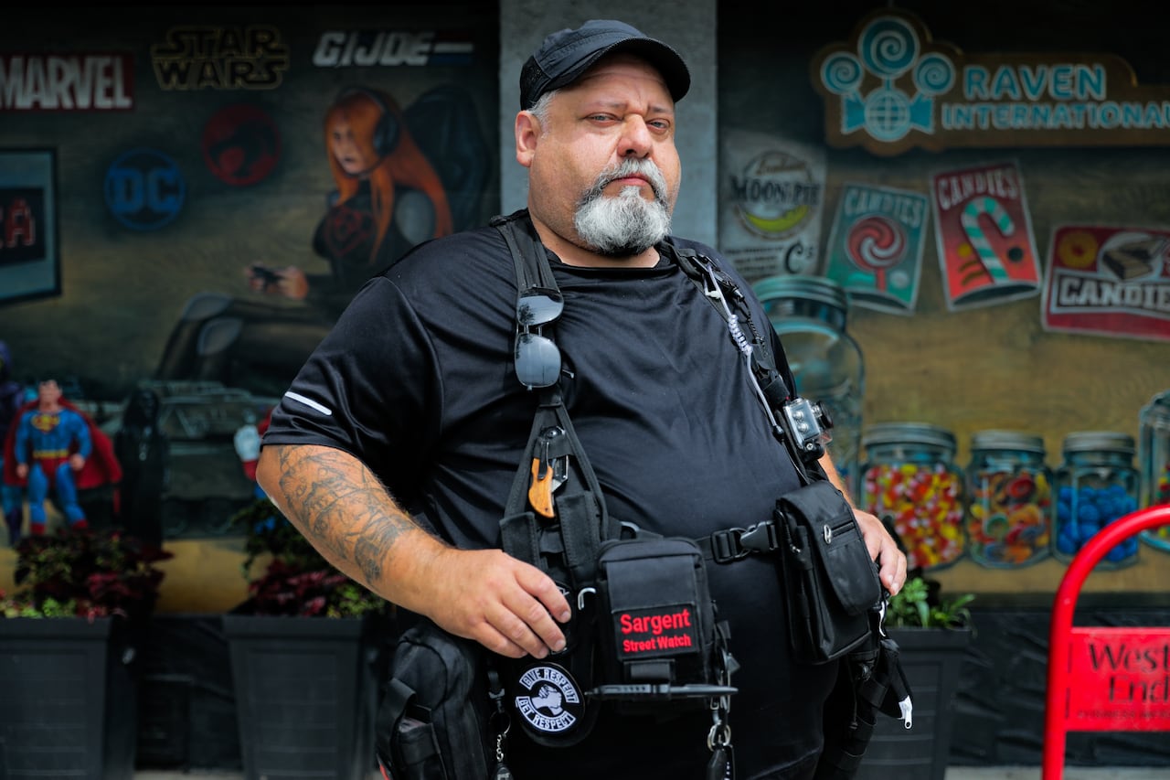 A man in a black shirt and black vest posing for a photo