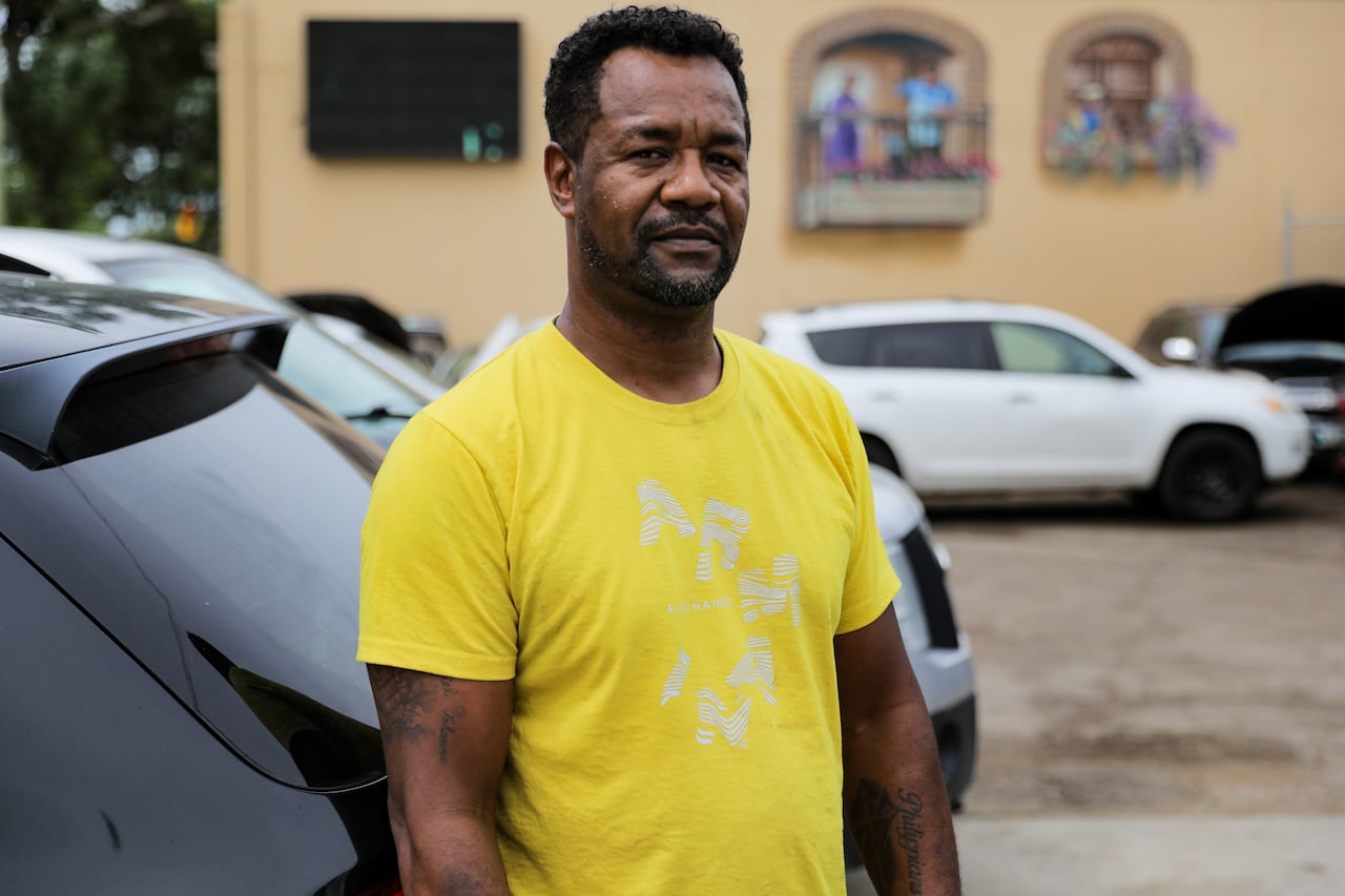A man in a yellow shirt poses for a photo at his business