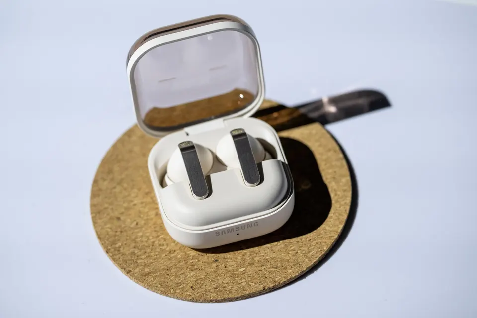 White Samsung Galaxy Buds in their charging case resting on a desk.