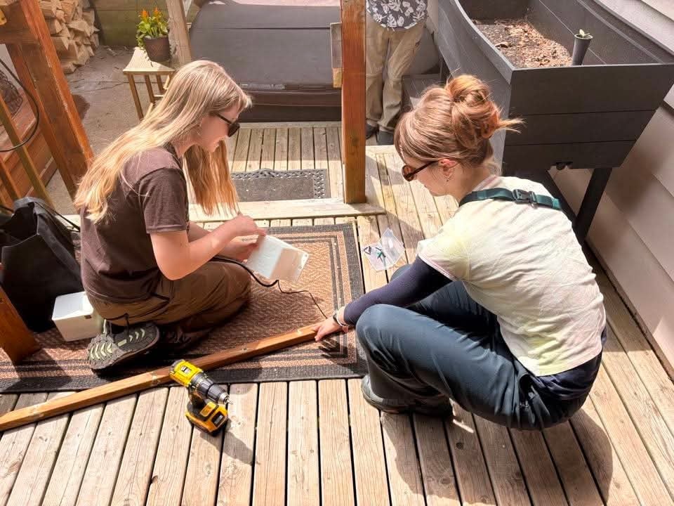 Madison Bygrove, left, and Natalie Emerick work to install an acoustic device at a house in Dartmouth, N.S.