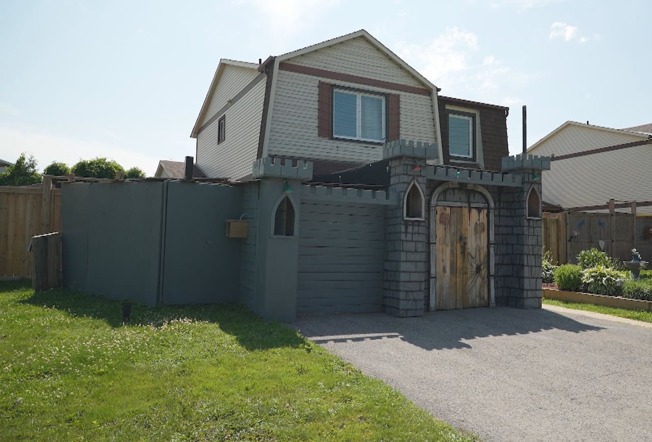 A grey painted castle on the front of a suburban home.