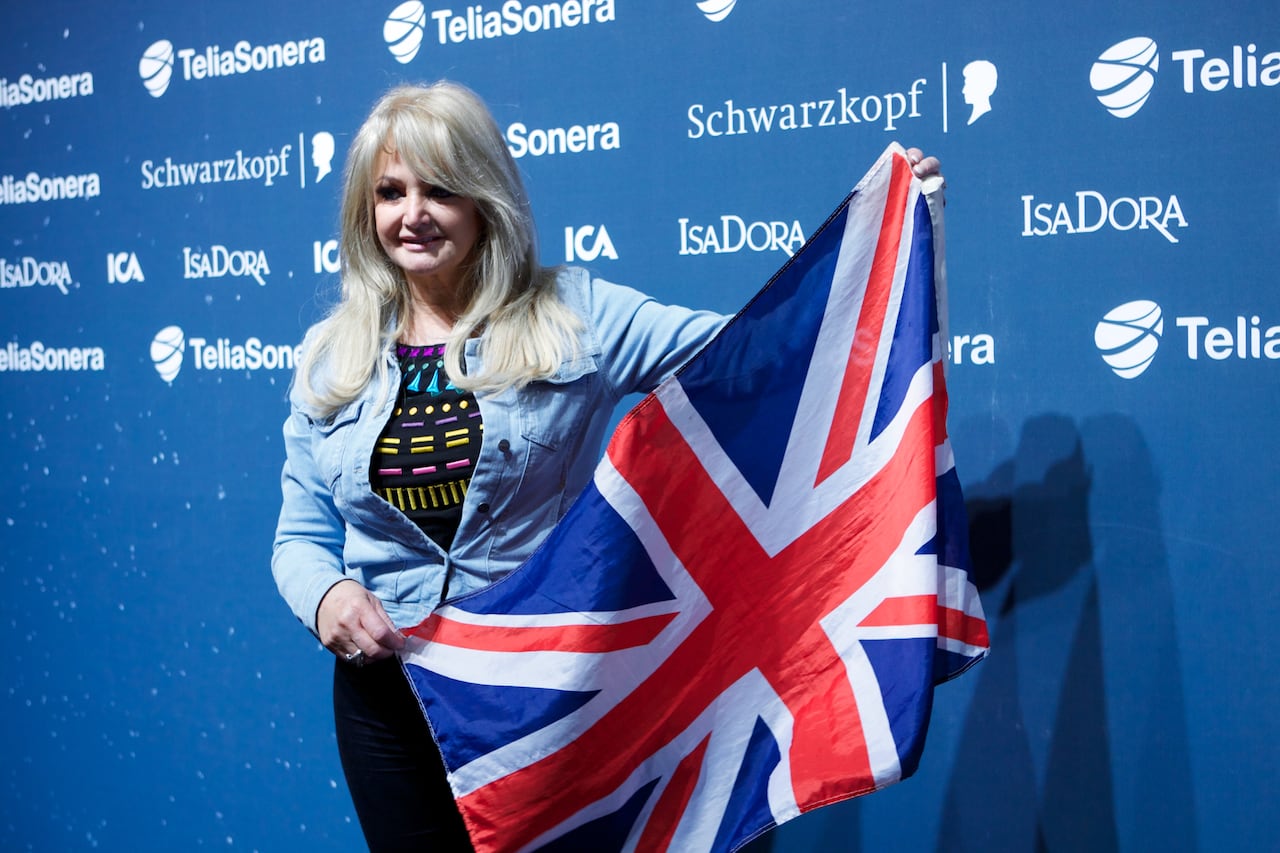 A blonde-haired woman is shown holding a British flag.