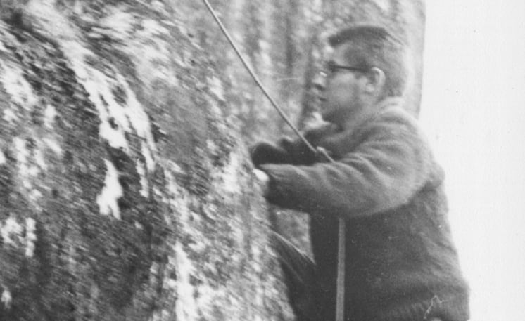 A black and white photo of a man on a rock face.