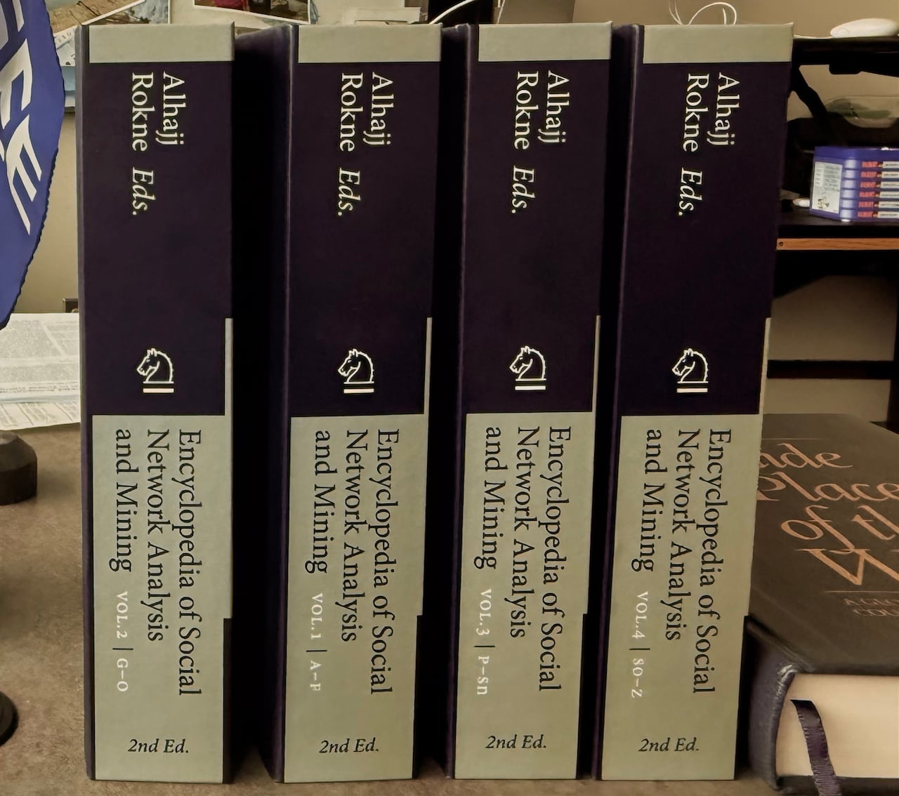 Four encyclopedias lined up on a desk.