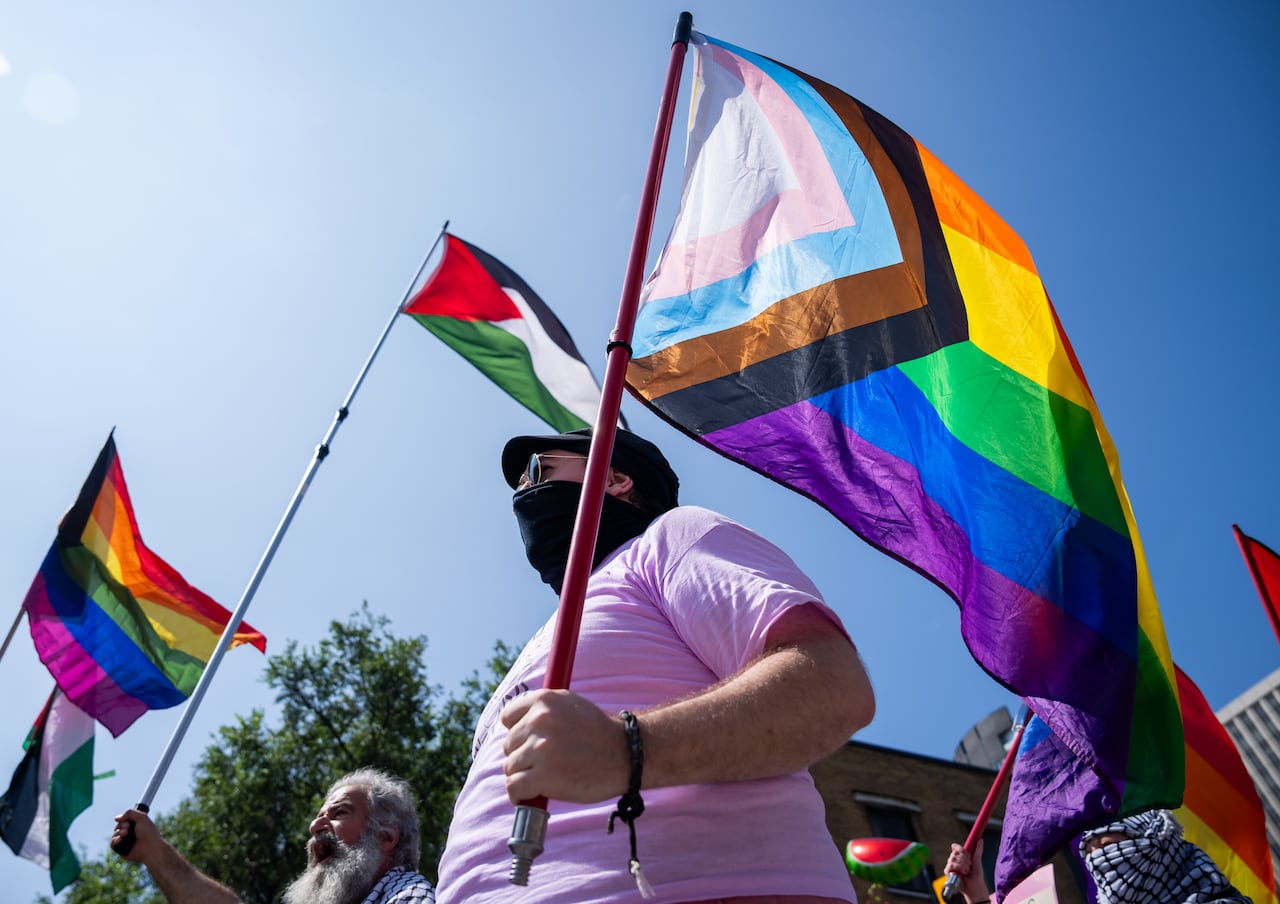 Marchers carry several flags outdoors during a parade.