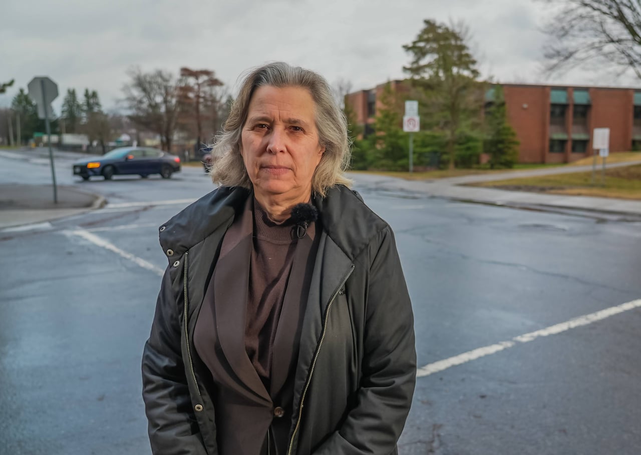 A trustee stands in front of a school.