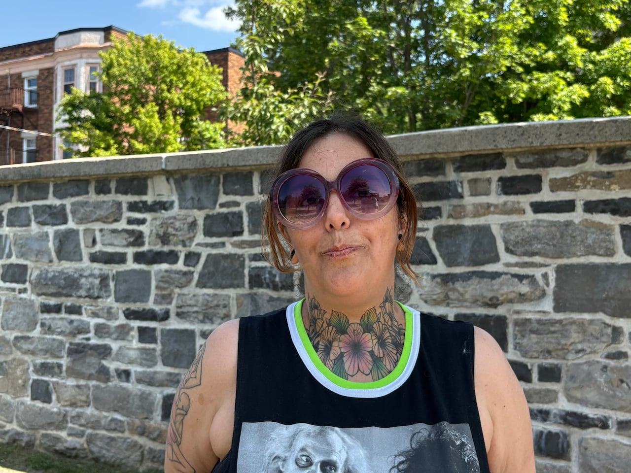 A woman in a black tank top and purple sunglasses