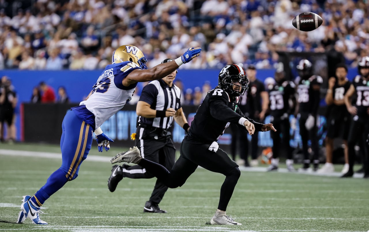 Ottawa Redblacks quarterback Dru Brown, in black, releases the football ahead of an onrushing Winnipeg Blue Bombers pass rusher.