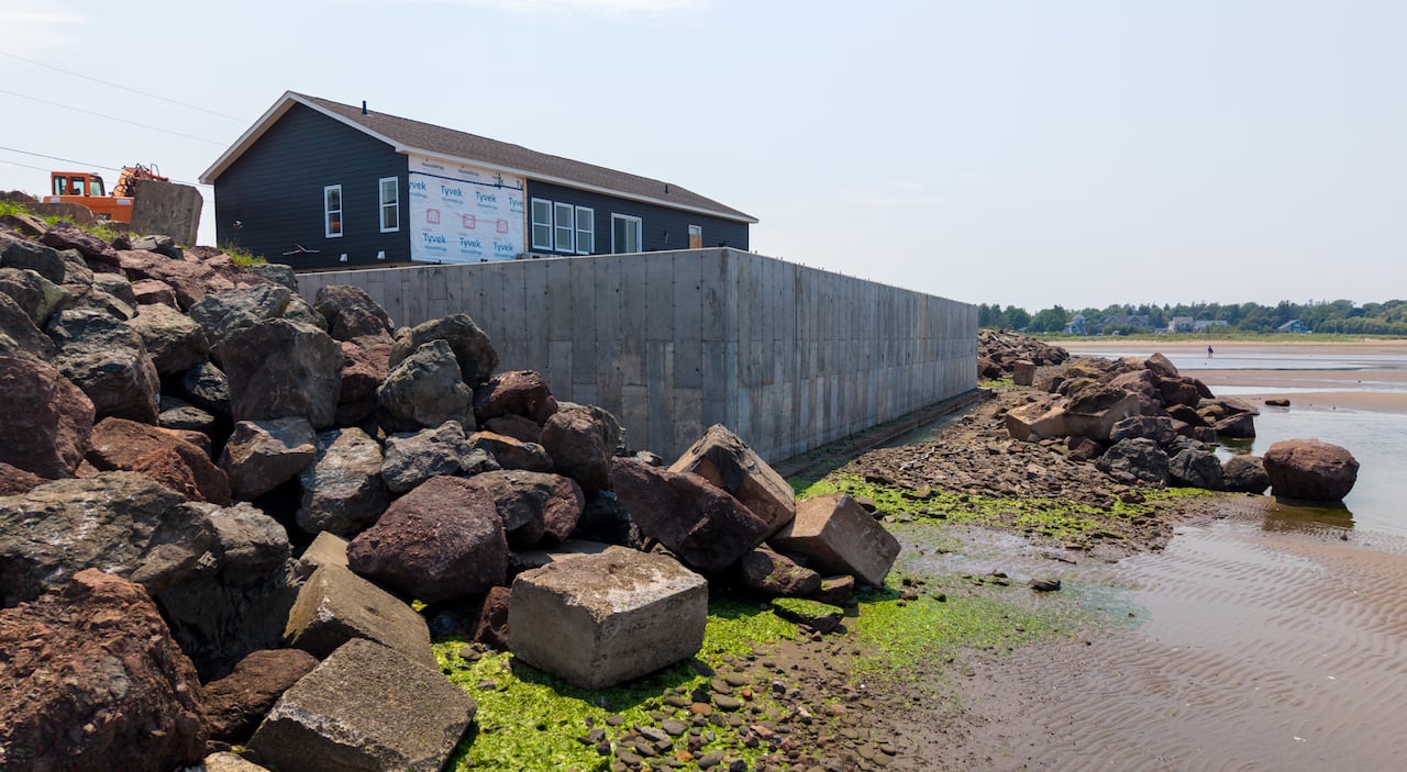 A view of the wall from the shore, with piles of rocks in front and to each side.