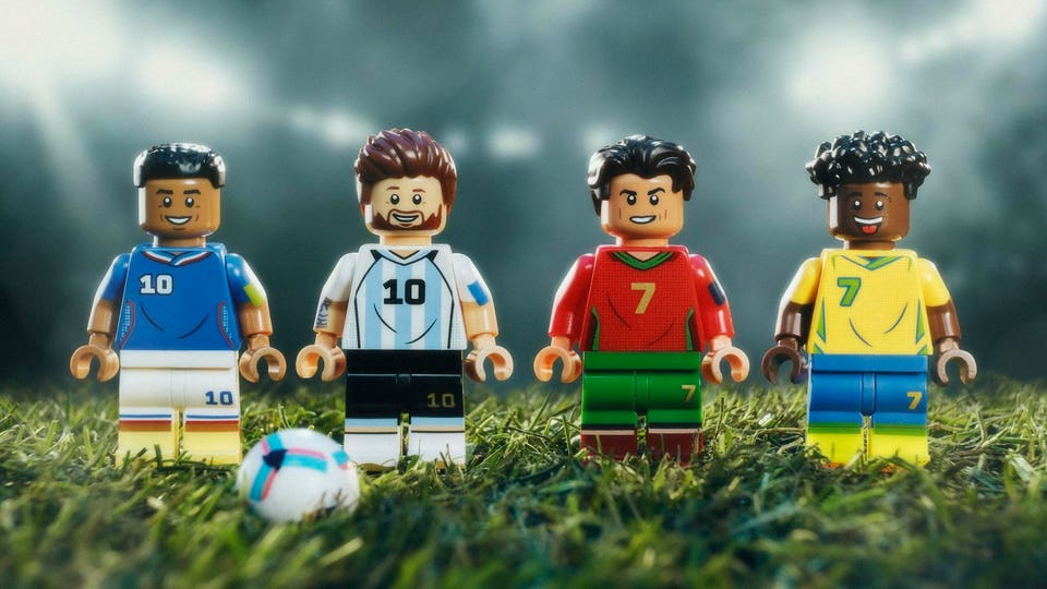 LEGO minifigures of Kylian Mbappé, Lionel Messi, Cristiano Ronaldo, and Vinicius Jr stood on grass.
