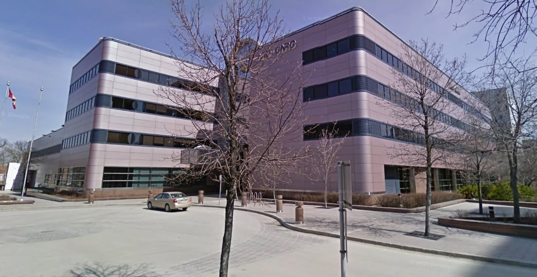 A modern, curved office building is seen from the street.