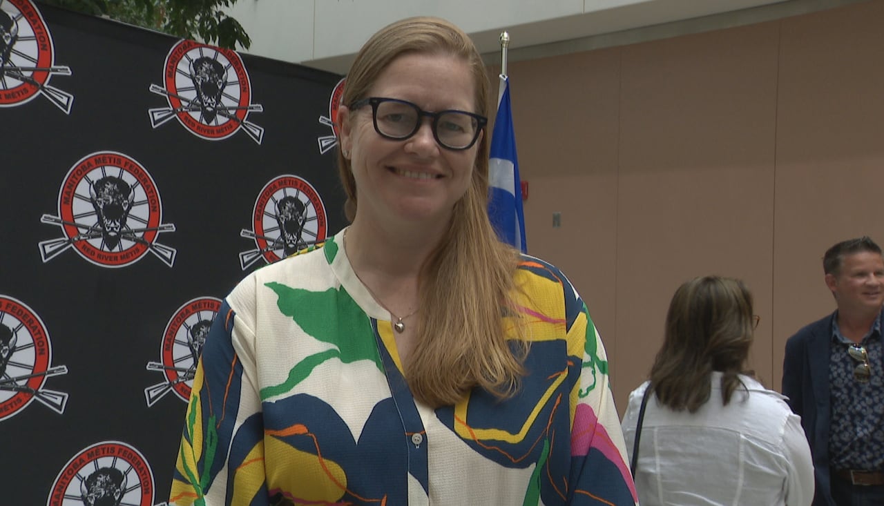 A woman with long hair and glasses smiles.