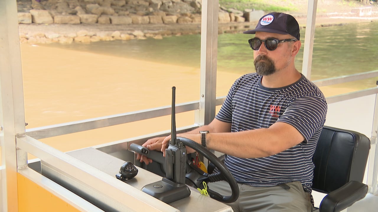A man in sunglasses steers a boat.
