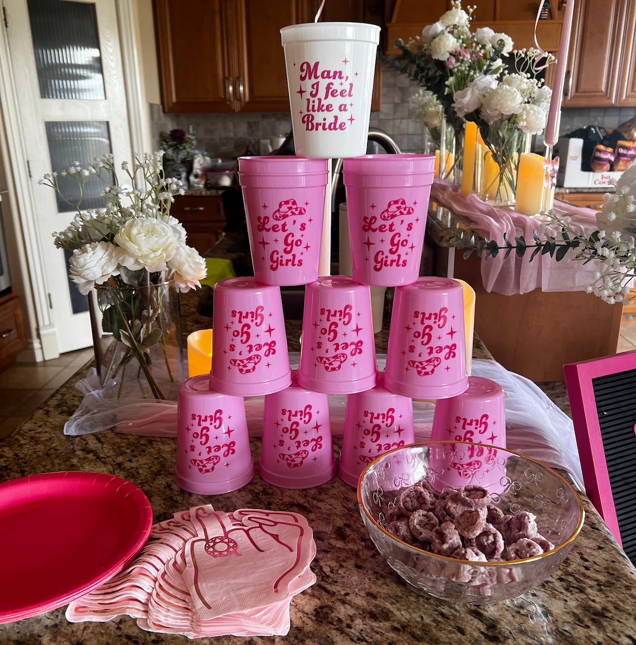 A stack of pink cups on a counter, with a white cup on top that says 'man, I feel like a bride'
