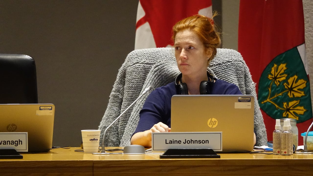 A city councillor sits at their desk and listens during a meeting.