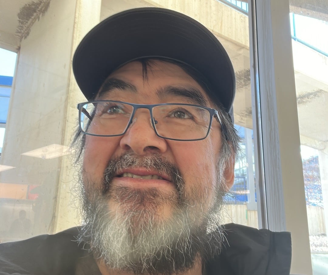 a man,  Allen Niptanatiak looks off to the distance in a single photo of himself