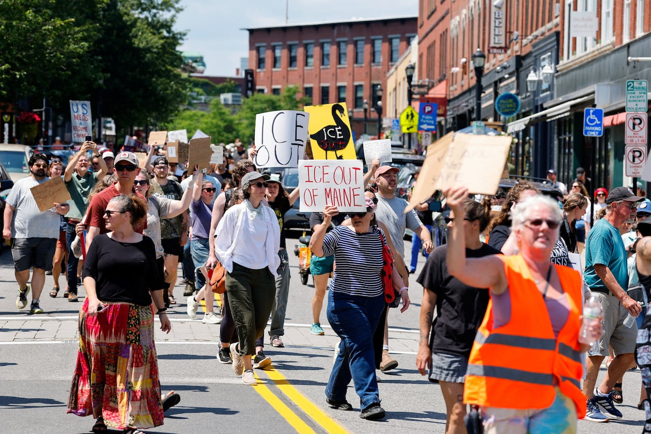 People hold signs and walk along a road.