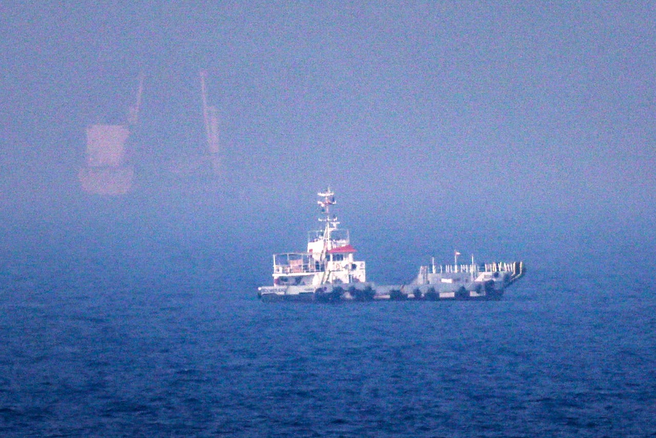 A freighter is shown in a blue body of water from a distance.
