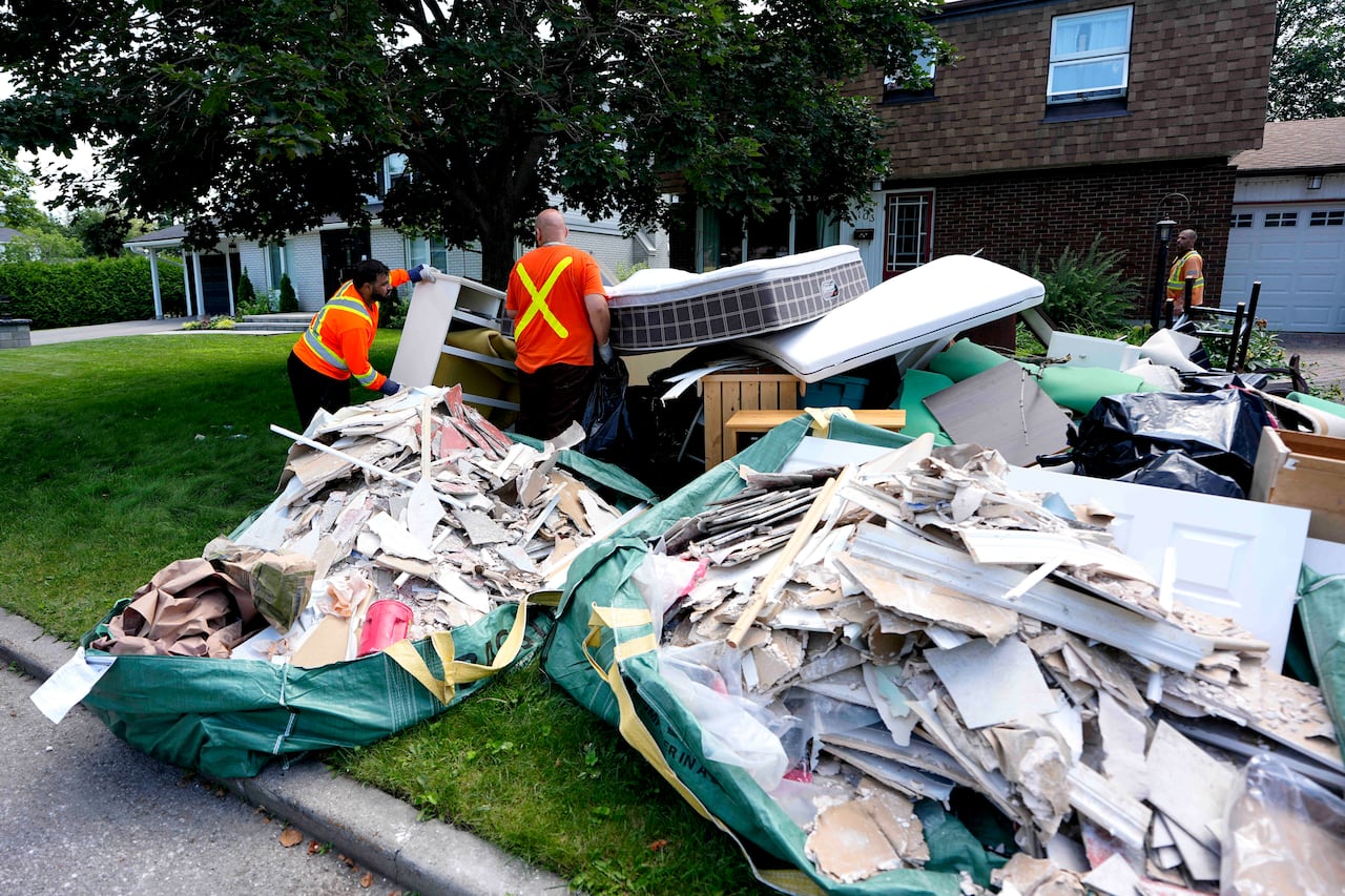 Municipal garbage contractors remove garbage from homes that flooded during the storm on Canada Day, in the Qualicum – Graham Park neighbourhood of Ottawa, on Tuesday, July 7, 2026.