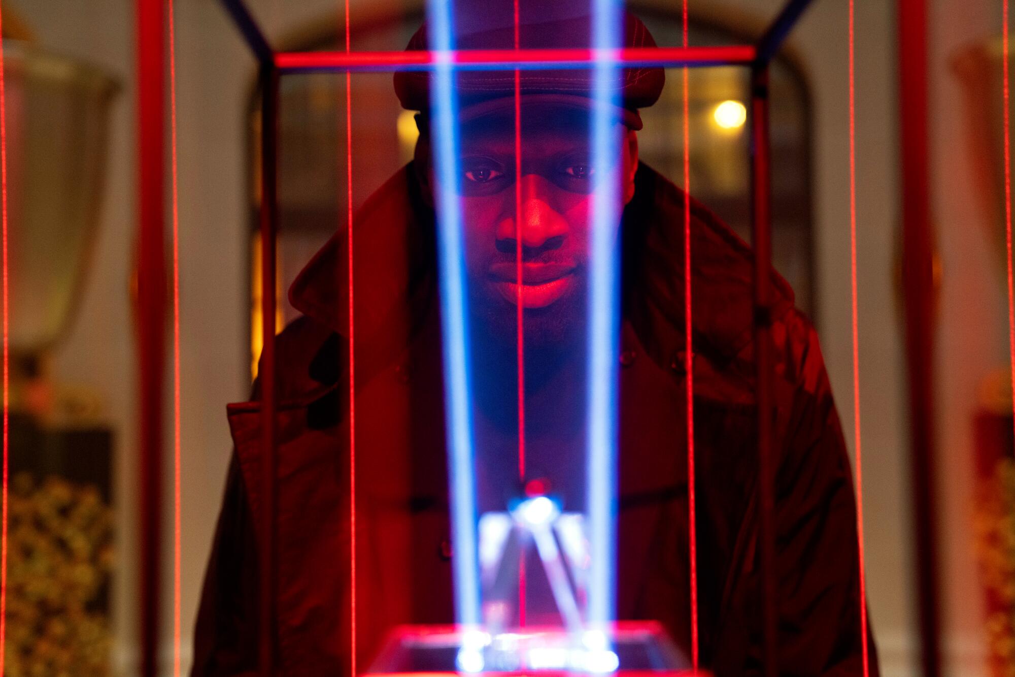 A man stands behind a jewel on display under museum censors. 