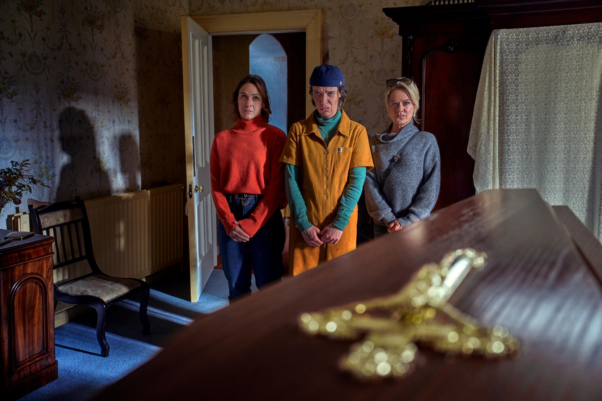 Three women stand near a coffin in "How to Get to Heaven From Belfast." 