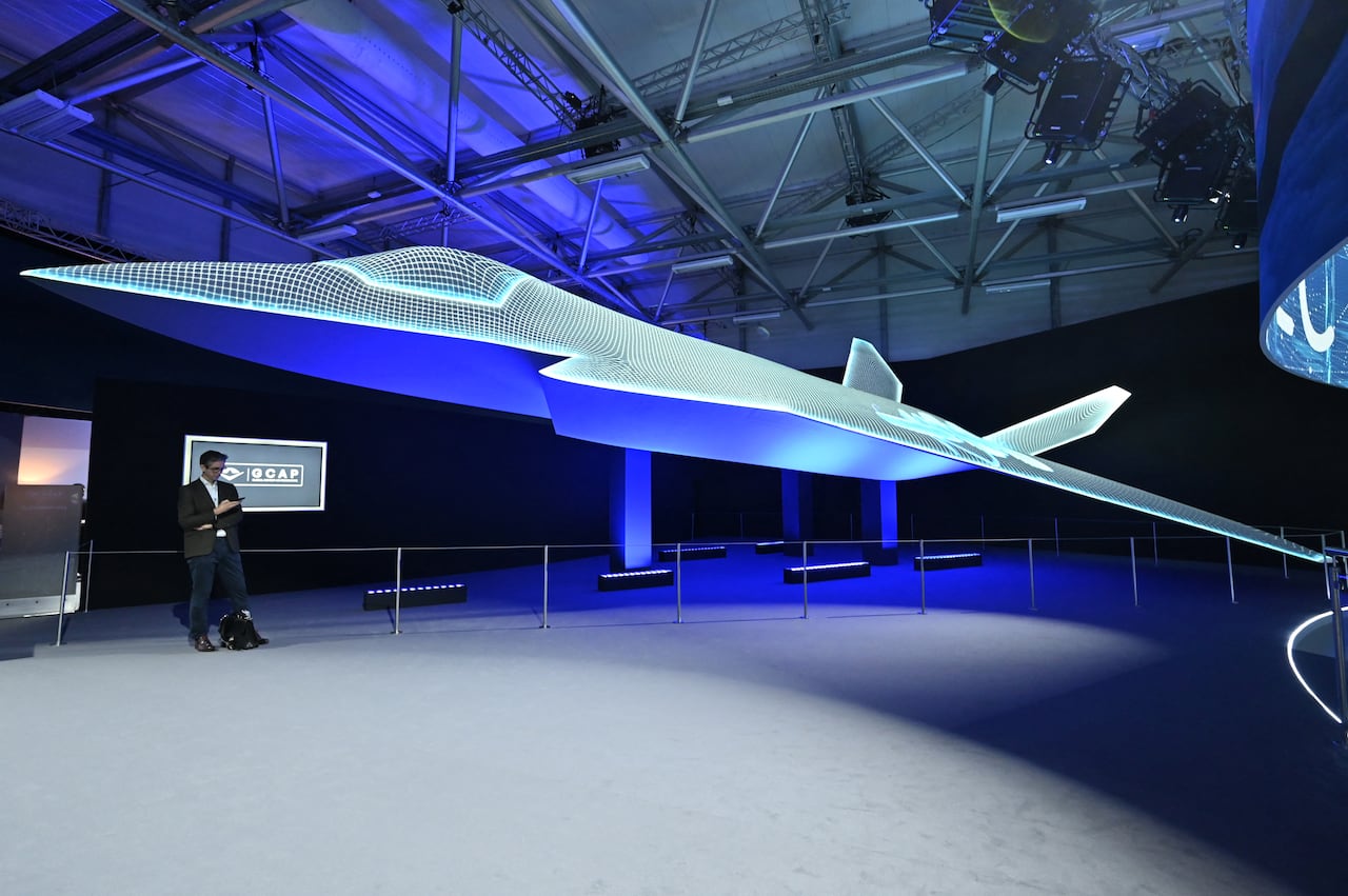 A person stands beside the Global Combat Air Programme (GCAP) 6th generation fighter jet concept design on the opening day of the Farnborough International Airshow 2024, south west of London, on July 22, 2024.