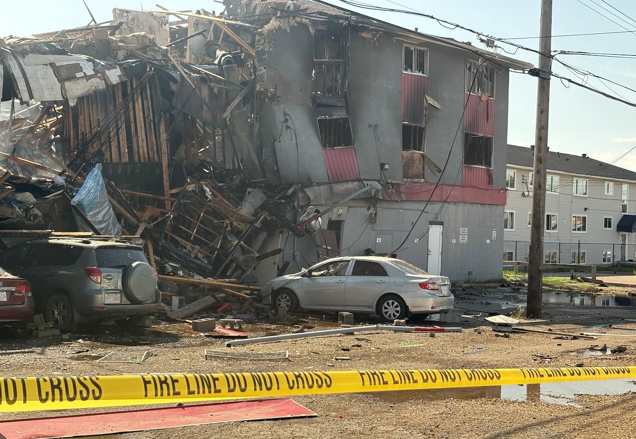 Three vehicles sit next to a destroyed building.