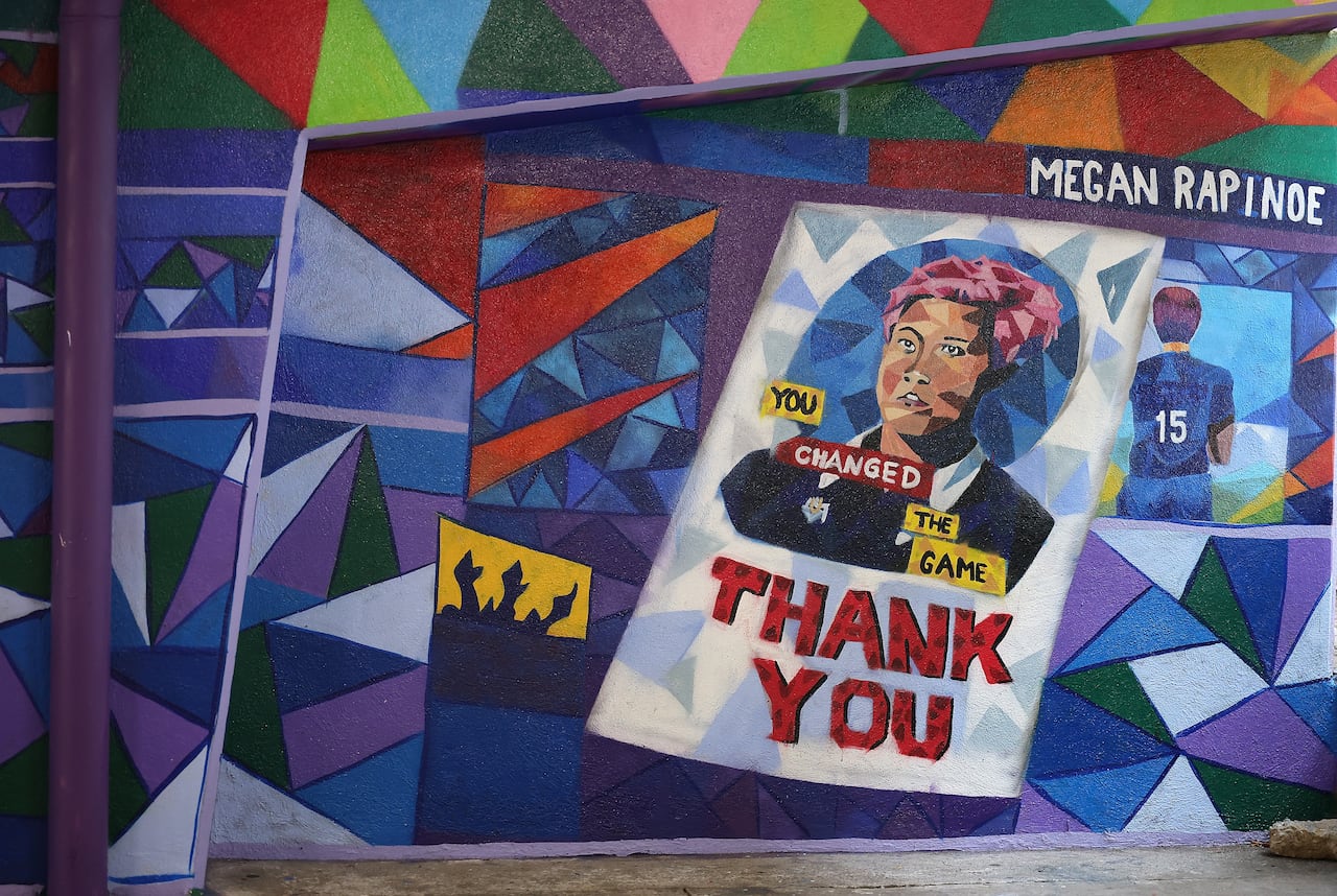 A colourful mural that includes a painting of a person with pink hair. It says: you changed them game, thank you, and Megan Rapinoe