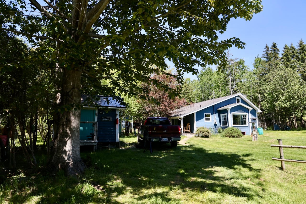 A building and a shed can be seen with a pickup truck out front.