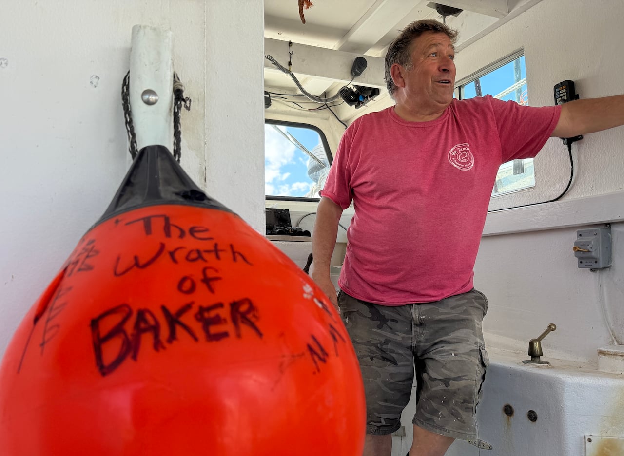 A man can be seen inside a boat. Next to him is a buoy that reads "The Wrath of Baker"