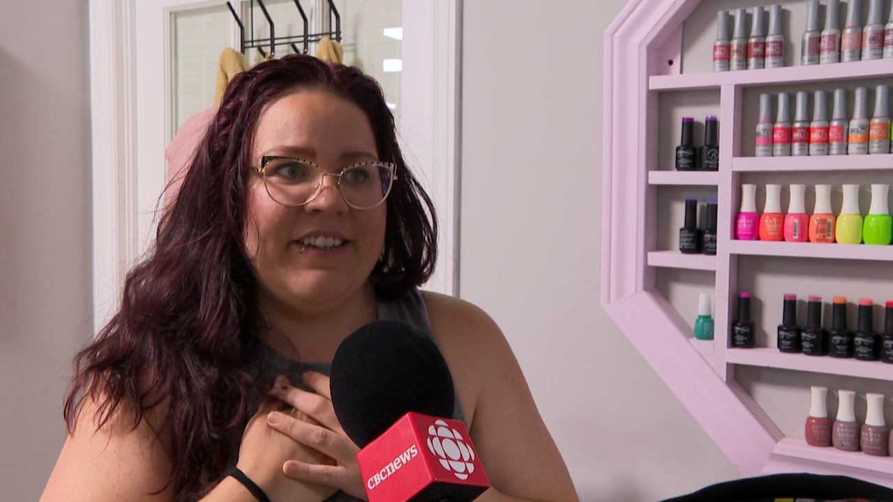 Woman holds chest while speaking into microphone